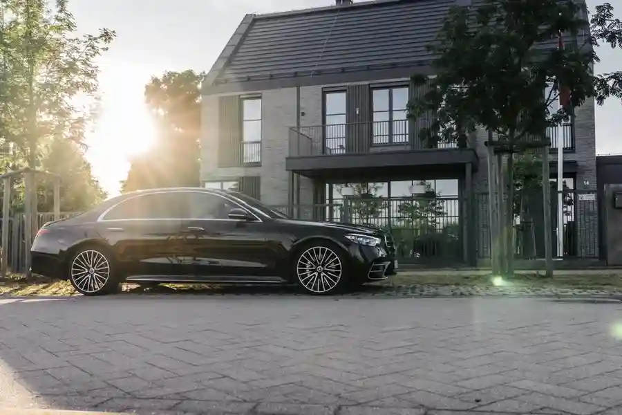 Luxury car Mercedes-Benz S-Class W223 parked in front of a modern private house. The owner uses a chauffeur service for airport transportation.